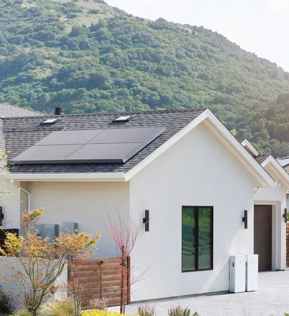 Solar-panels-on-home White modern home with rooftop solar panels and a wall-mounted home battery