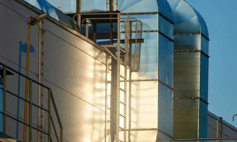 commercial-scale Large metal ventilation ducts and access stairs on the side of an industrial building